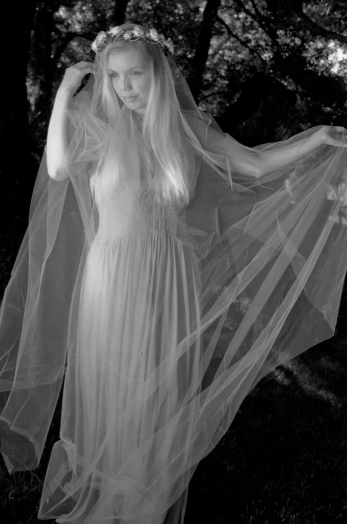 Femme couronnée de fleurs sous un long voile, en forêt