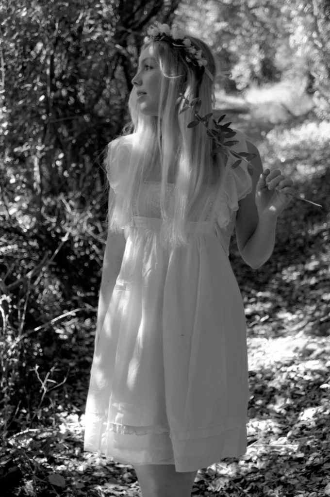Femme en robe blanche dans un sous-bois, en noir et blanc