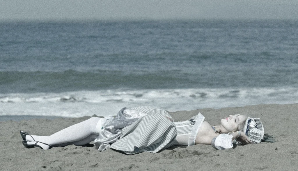Femme en robe à rayures XVIIIe allongée sur le sable