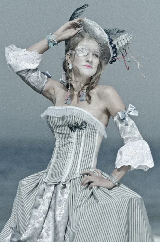 Femme en robe à paniers et perruque XVIIIe sur une plage