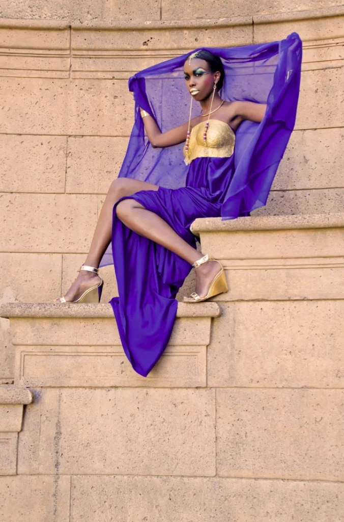 Femme en robe violette assise sur une corniche de pierre