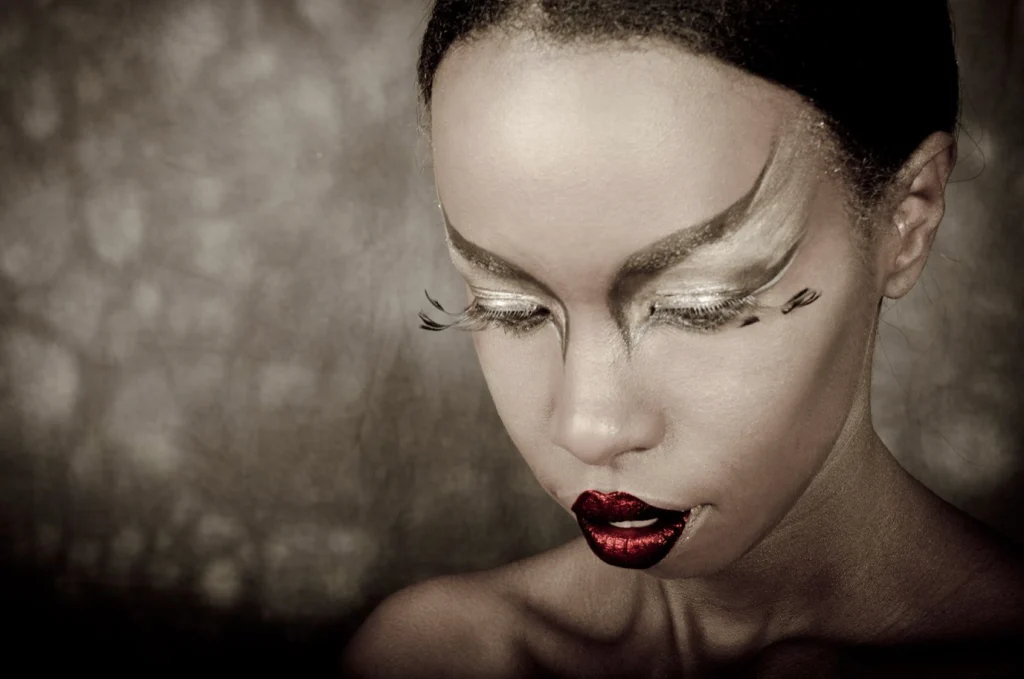 Visage au maquillage doré et lèvres rouges, paupières baissées