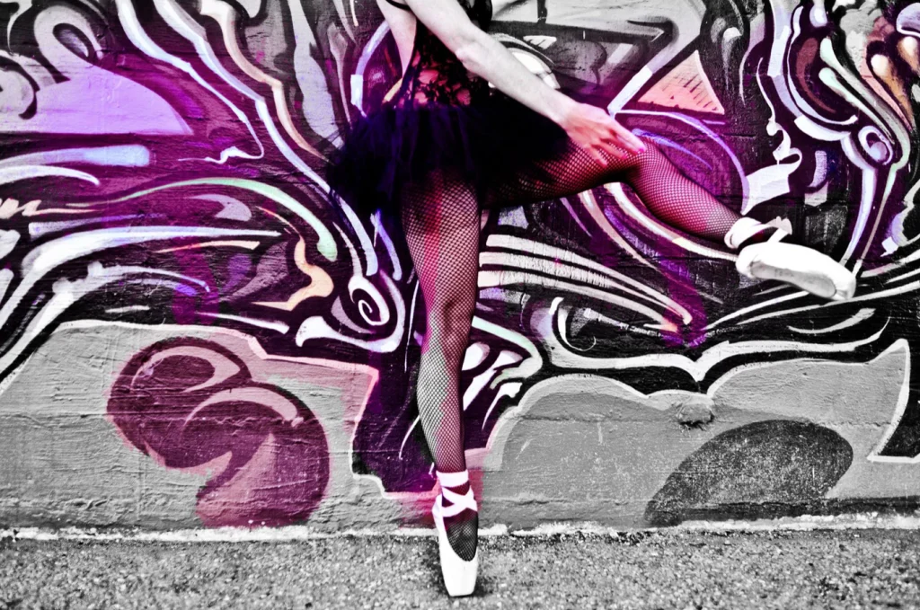Jambe de ballerine en pointes et bas résille devant des graffitis