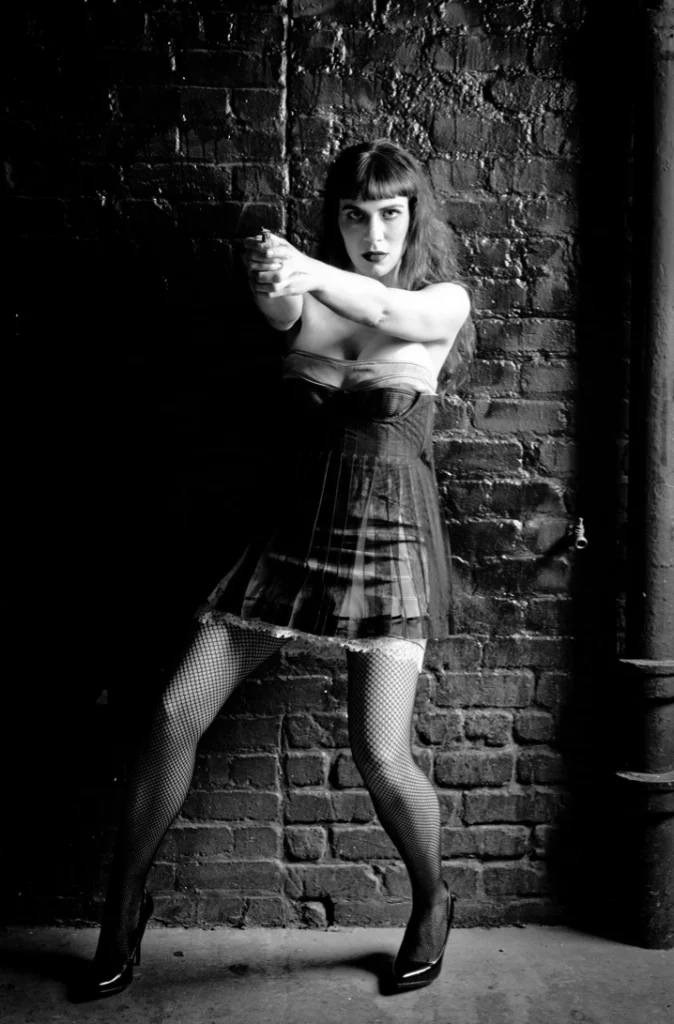 Femme en robe des années 1920 dansant devant un mur de briques