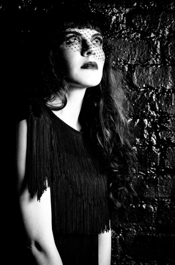 Femme à la voilette en robe à franges, en noir et blanc