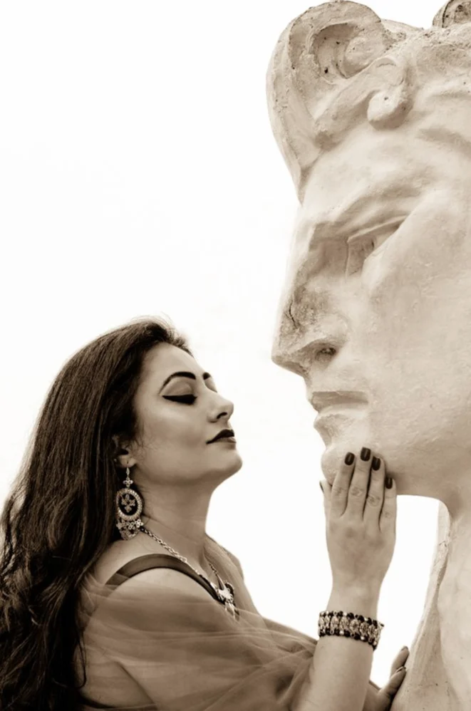 Femme de profil face à une statue de visage antique