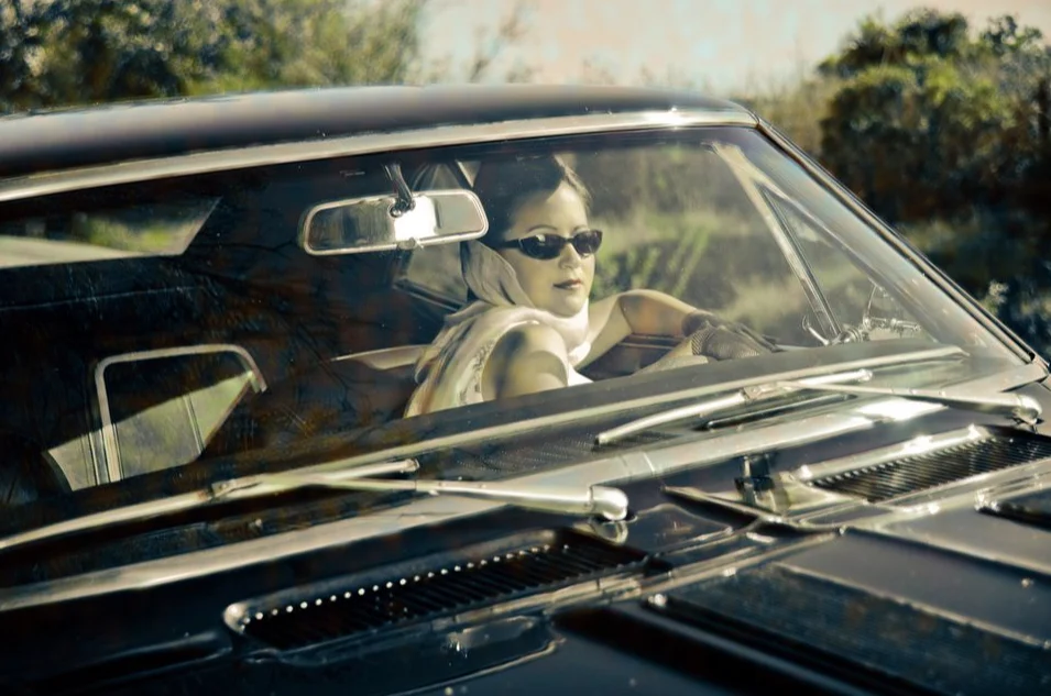 Femme en lunettes de soleil au volant d'une voiture ancienne