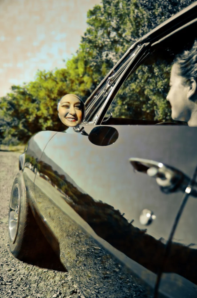 Femme souriante à la portière d'une voiture ancienne