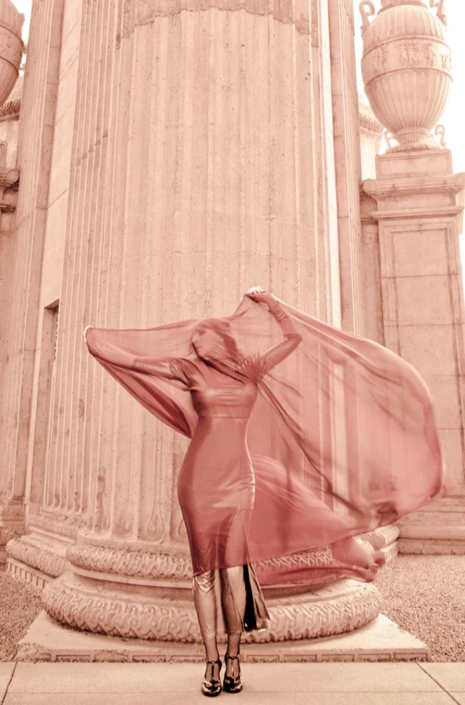 Femme faisant voler un voile rouge entre deux colonnes