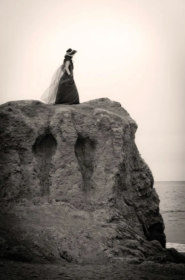 Silhouette voilée debout au sommet d'un rocher au bord de la mer