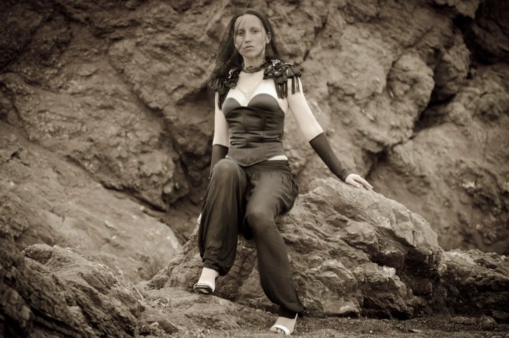Femme assise sur un rocher en pantalon ample et bustier