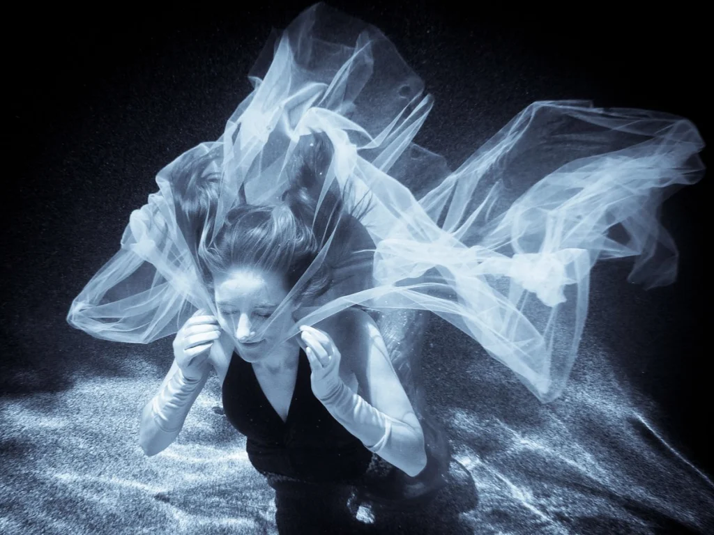 Femme sous l'eau enveloppée d'un voile blanc