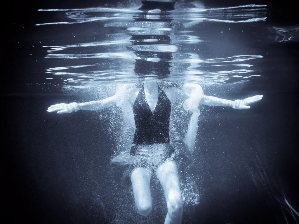 Femme sous l'eau, bras écartés, vue sous la surface