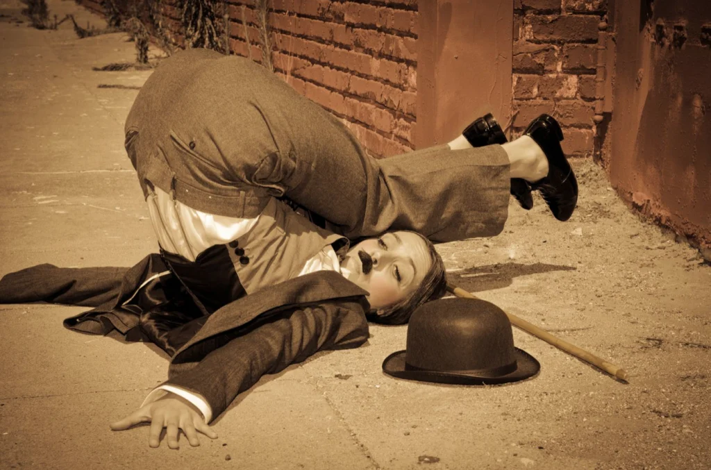 Charlot tombé au sol, chapeau melon et canne à côté