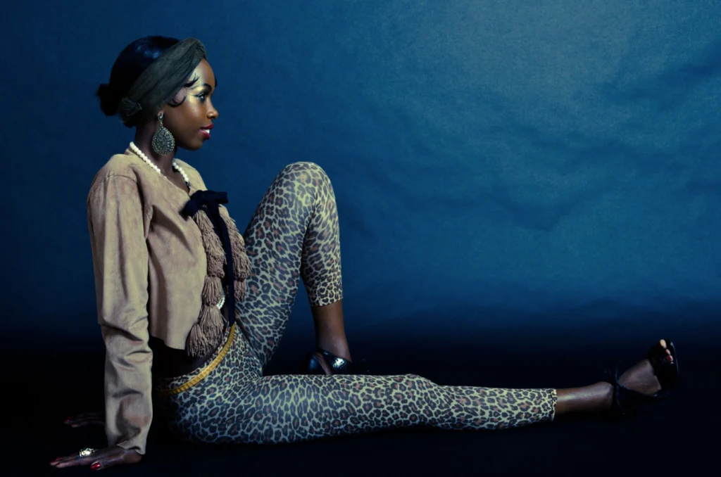 Femme assise en veste et pantalon léopard sur fond bleu
