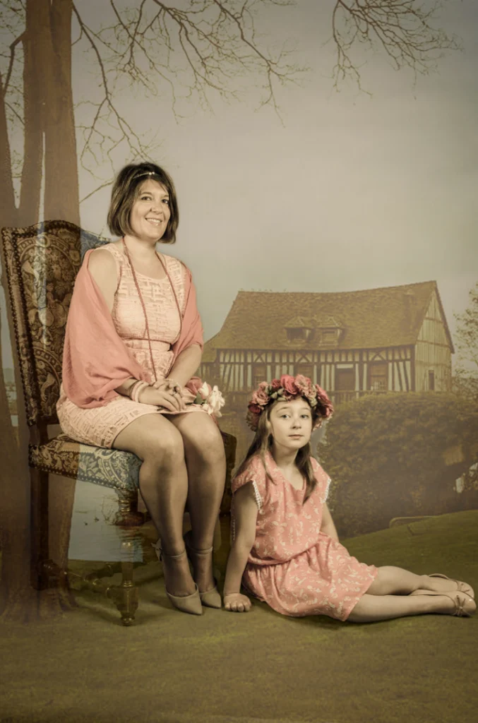 Mère et fille assises devant un décor peint de maison à colombages