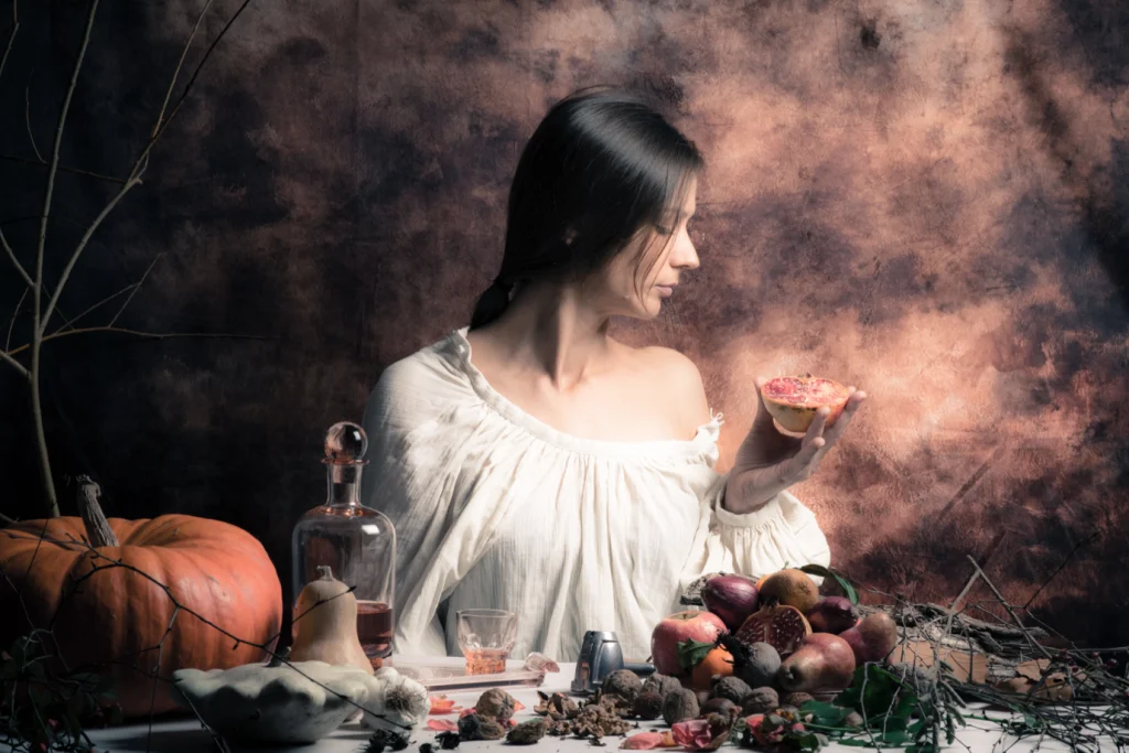 Nature morte d'automne : jeune femme en blouse blanche tenant une grenade, citrouilles et fruits