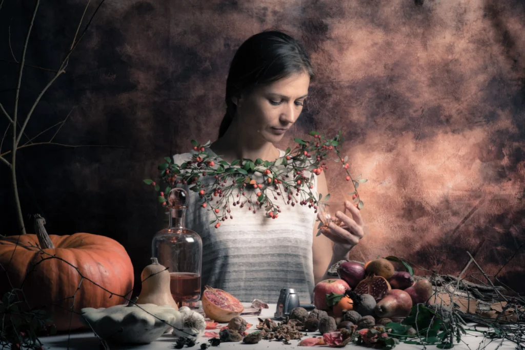 Jeune femme couronnée de feuillage devant une table de fruits d'automne