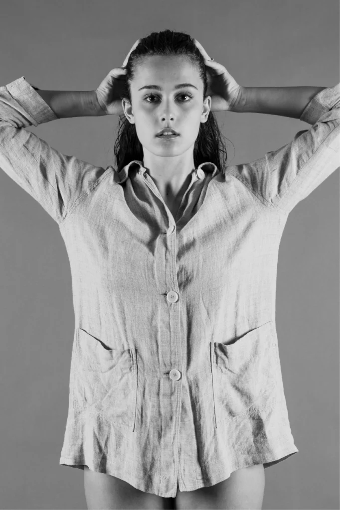 Jeune femme en chemise de lin, les mains derrière la tête, en noir et blanc