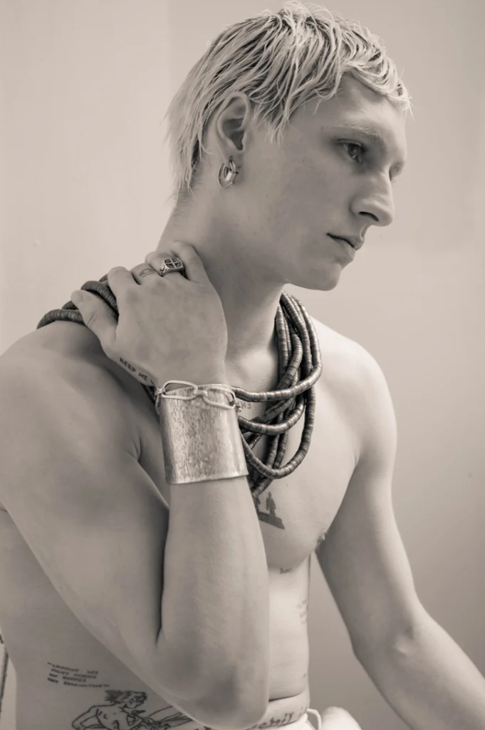 Jeune homme torse nu portant des bracelets, en noir et blanc