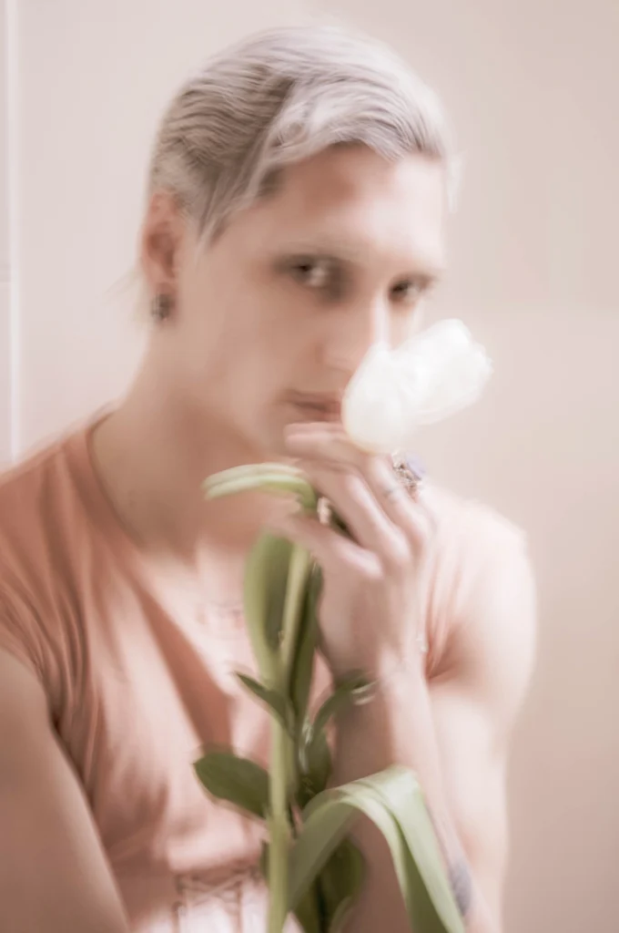 Jeune homme respirant une fleur blanche