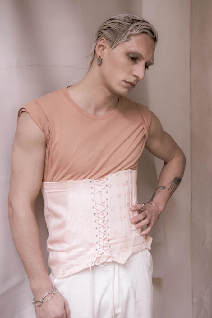 Jeune homme en corset rose et t-shirt pêche