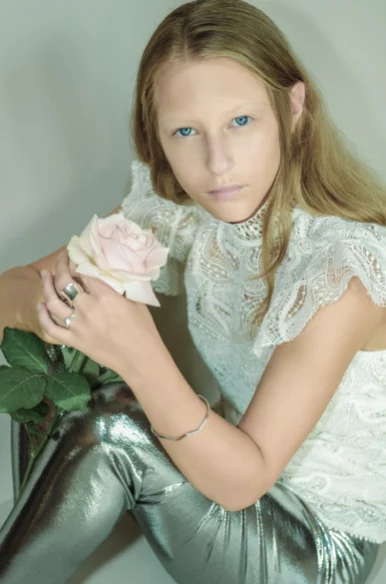 Jeune femme en dentelle tenant une rose rose