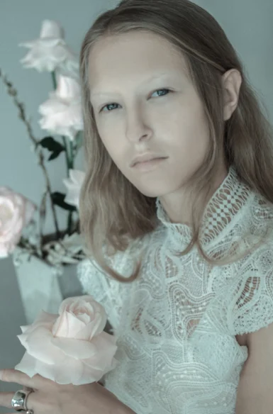 Portrait d'une jeune femme en dentelle blanche, roses pâles au premier plan